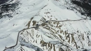 Dolomitlerin güneşli bir günde İtalya 'da karla kaplı dağların havadan görünüşü, Canazei, insansız hava aracı bakış açısı, kıvrımlı yol, beyaz bulutlu mavi gökyüzü, dünyada ünlü bir yer, UNESCO anıtı.