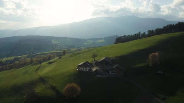 Vista aérea de prados verdes improváveis de Alpes italianos, encostas verdes das montanhas, Bolzano, nuvens enormes sobre um vale, topos de telhado de casas, Dolomites no fundo, raios de sol através de nuvens — Vídeo de Stock