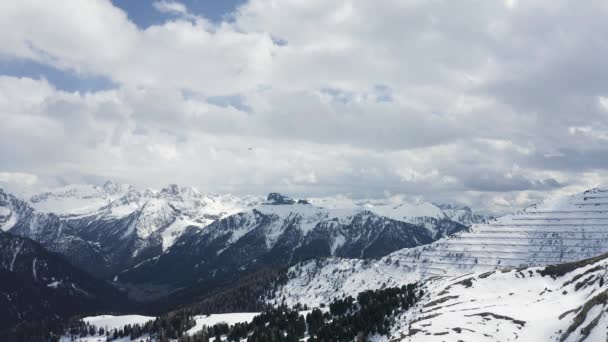 Italia, Dolomiti, Canazei, Il drone volante sospeso sulle montagne, sullo sfondo montagne innevate, la strada tortuosa, il cielo azzurro con nuvole bianche, tempo soleggiato, nessuno — Video Stock