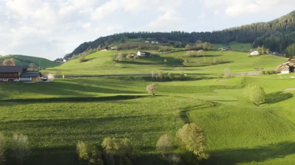 Widok z lotu ptaka na nieprawdopodobne zielone łąki Alp Włoskich, zielone zbocza gór, Bolzano, ogromne chmury nad doliną, dachy domów, Dolomity na tle, promienie słońca przez chmury — Wideo stockowe