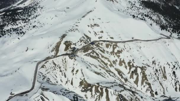 Letecký pohled na zasněžené pohoří Dolomity v Itálii za slunečného dne, Canazei, vyhlídka na dron, klikatá cesta, modrá obloha s bílými mraky, známé místo na světě, památník UNESCO — Stock video