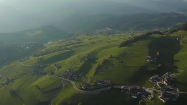 Letecký pohled na nepravděpodobné zelené louky italských Alp, zelené svahy hor, Bolzano, obrovské mraky nad údolím, střechy domů, Dolomity na pozadí, slunce svítí mraky — Stock video