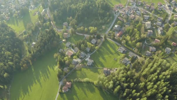 Flygfoto över osannolika gröna ängar av italienska Alperna, gröna sluttningar av bergen, Bolzano, stora moln över en dal, tak toppar av hus, Dolomiter på bakgrunden, solsken genom moln — Stockvideo