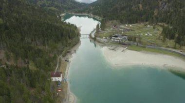 İtalya 'nın Olasılıkdışı hava manzarası, İHA' lar göl suyunun üzerinde alçaktan uçuyor, boş bir sahil, bulutlu hava, kıyı şeridi, köprü.