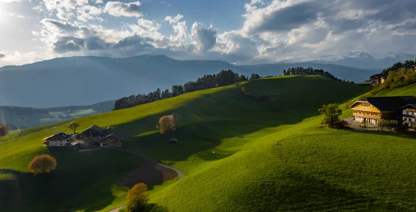 Aerial view of improbable green meadows of Italian Alps, green slopes of the mountains, Bolzano, huge clouds over a valley, roof tops of houses, Dolomites on background, sunshines through clouds — Stock Photo, Image