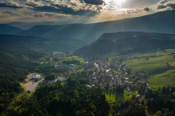 Aerial view of improbable green meadows of Italian Alps, cityscape of Bolzano, huge clouds over a valley, roof tops of houses, Dolomites on background, sunshines through clouds — Stock Photo, Image