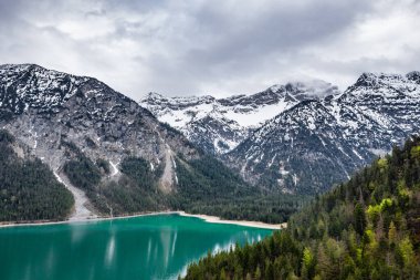 İtalya 'nın Olasılıkdışı hava manzarası, İHA' lar göl suyunun üzerinde alçaktan uçuyor, boş bir sahil, bulutlu hava, kıyı şeridi, köprü.