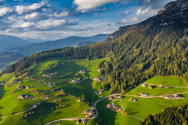 Aerial view of improbable green meadows of Italian Alps, green slopes of the mountains, Bolzano, huge clouds over a valley, roof tops of houses, Dolomites on background, sunshines through clouds — Stock Photo, Image