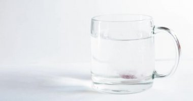 Cam şeffaf bir bardağa atılan köpüklü tablet, beyaz bir zemin üzerinde cam, soğuk kırmızı şarap için bir hap, kabarcıklar yükselir, cam bir sıçrama