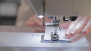 Usta terzinin yavaş çekim videosu ve otomatik dikiş makinesinin iğnesi, iyi manikür, kamera etrafta dolaşıyor.