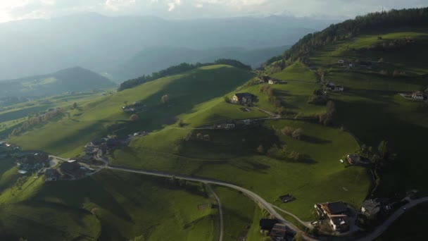 イタリアアルプスの信じられないほどの緑の牧草地、山の緑の斜面、ボルツァーノ、谷の上の巨大な雲、家の屋根の上、背景にドロマイト、雲を通して太陽の光 — ストック動画