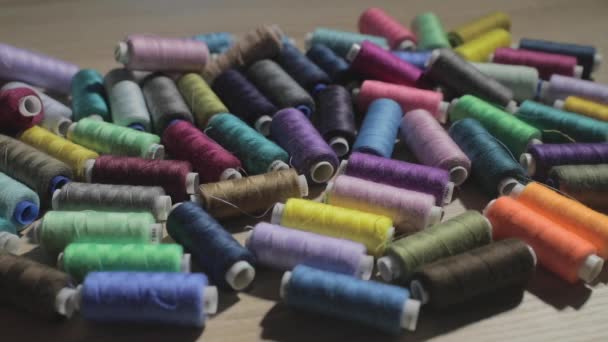 Slow motion video of rolls of strings of different color lie on a table, someone throws a roll of threads on a table, colorful — Stock Video