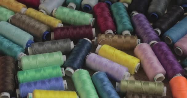 Slow motion video of rolls of strings of different color lie on a table, someone throws a roll of threads on a table, colorful — Stock Video