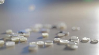 Masanın üzerindeki çeşitli renkli düğmelerin yavaş çekimleri. Plastikten yapılmış farklı renkli düğmeler. Dikiş malzemeleri, giysi aksesuarları, dikiş ipliği, dikiş düğmeleri, tekstil aksesuarları.