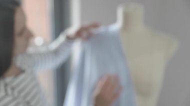 Giysi tasarımcısının yavaş çekim videosu dikiş ajansındaki bir mankenle çalışıyor, 46 beden, mavi kumaşla dikiş ustasının elleri, kırmızı uçlu iğneler dikiyor.