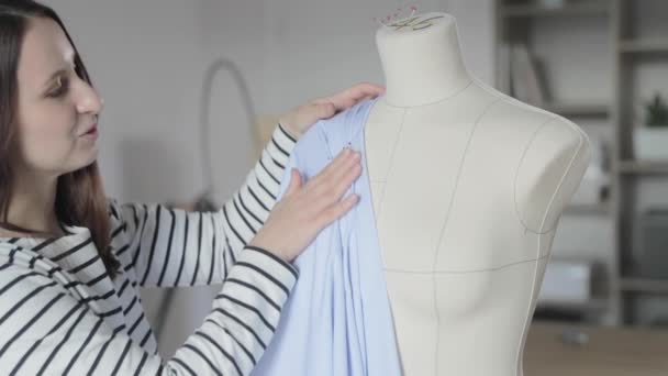 Filmik projektanta odzieży pracuje z manekinem w agencji szycia, rozmiar 46, ręce mistrza w szyciu z niebieskiej tkaniny, igły do szycia z czerwoną końcówką — Wideo stockowe