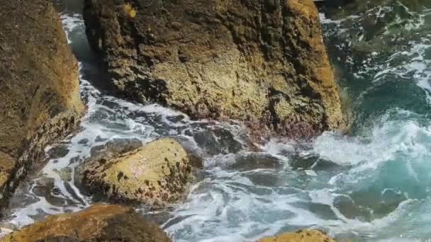 Olas rompen alrededor de la costa rocosa de la costa azul, salpicaduras, agua clara, agua azul, lugar famoso — Vídeos de Stock