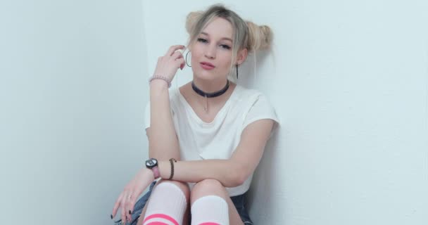 Das blonde Mädchen der Teenager in weißem T-Shirt posiert, flirtet, lächelt, zappelt, ein Haarkleid in Form von Trauben, einen Choker am Hals, Armbänder an den Händen — Stockvideo