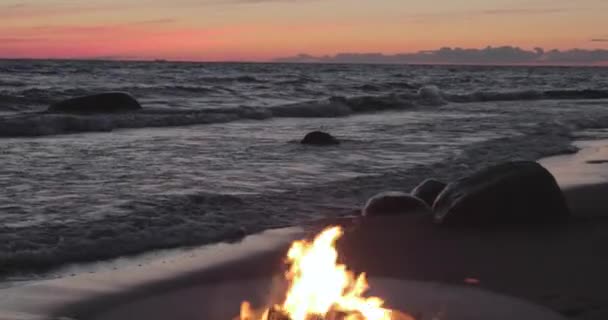 A paisagem do belo metal em volta de uma lareira na costa arenosa com uma onda de maré ao pôr do sol, pedras, tranquilidade, o sol cai, lenha, carvões vermelhos, ninguém — Vídeo de Stock