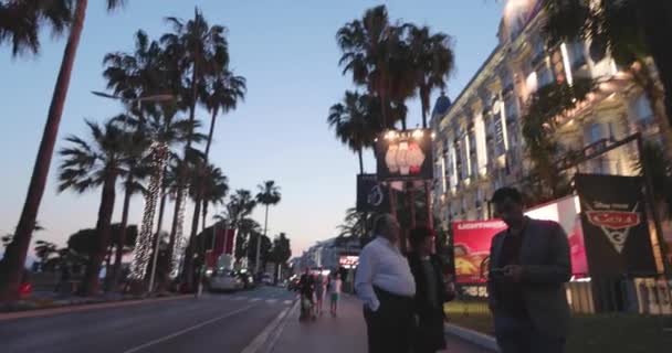 Francia, Cannes, 27 de mayo de 2017: El hotel Carlton por la noche durante el Festival de Cannes, sucursal de palmeras, famoso evento, damas y caballeros en vestidos de noche, cafés abarrotados, escoltas con la policía — Vídeos de Stock