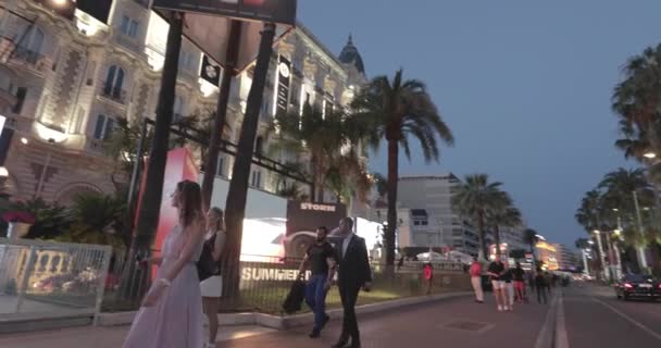 França, Cannes, 27 de maio de 2017: O hotel Carlton à noite durante o Festival de Cannes, ramo de palmeiras, evento famoso, senhoras e senhores em vestidos de noite, cafés lotados, acompanhantes com a polícia — Vídeo de Stock