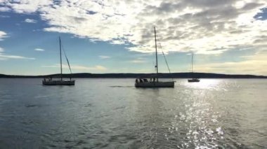 Yat yarışlarına katılanların sıralaması gün batımında bir başlangıç noktasına çıkıyor, Hırvatistan 'da bir yelkencilik yarışı, sudaki yelkenlerin yansıması