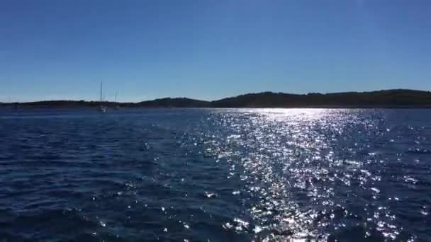 克罗地亚，亚得里亚海，帆船漂浮在平静的海面上，阳光映照在水面上，映衬着高山，天气晴朗，游艇划过 — 图库视频影像