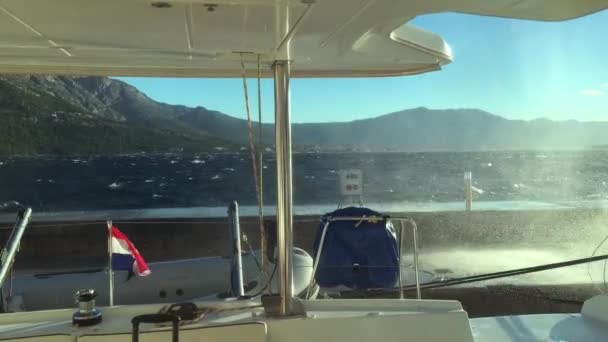 The view from a catamaran saloon on breaking waves about a pier in Korchulas port in a stormy weather, splashes, a strong wind blows into splashes on yachts, the Adriatic Sea, Croatia — Stock Video