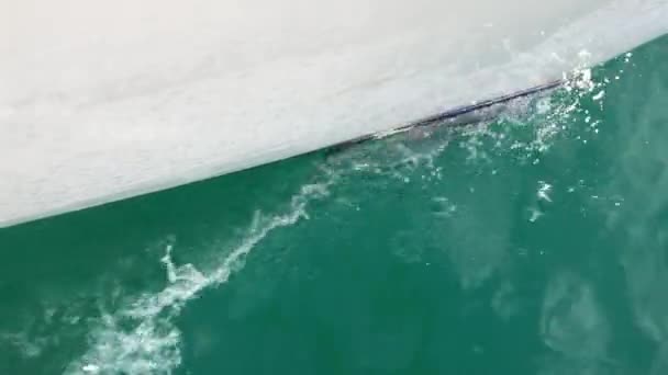 Le nez d'un voilier blanc coupe l'eau, éclaboussures de pulvérisation, éclat de l'eau sur la lumière du soleil, couleur verte, couleur vive — Video
