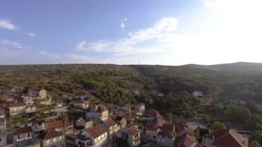 Hırvatistan 'ın Milna kentindeki liman manzarası, insansız hava aracı bakış açısı, ufukta tam bir gökkuşağı, adalar, park halindeki yatlar, balıkçı tekneleri, kırmızı çatılı pansiyonlar