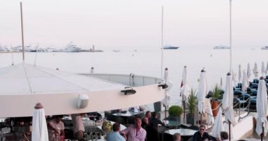 Fransa, Cannes, 27 Mayıs 2017: Günbatımında Cannes Film Festivali, sahil kafeleri, şemsiyeler, kalabalık kafeler, pembe gökyüzü