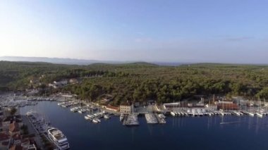 Hırvatistan 'ın Milna kentindeki liman manzarası, insansız hava aracı bakış açısı, ufukta tam bir gökkuşağı, adalar, park halindeki yatlar, balıkçı tekneleri, kırmızı çatılı pansiyonlar