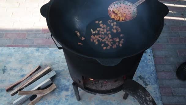 Braten von Hammelfett bis zum Zustand von Crackern, irgendein Stadium der Zubereitung eines usbekischen Nationalgerichts pilaf, Schaufel für Lebensmittel, Kessel, Feuer, Brennholz, im Freien — Stockvideo