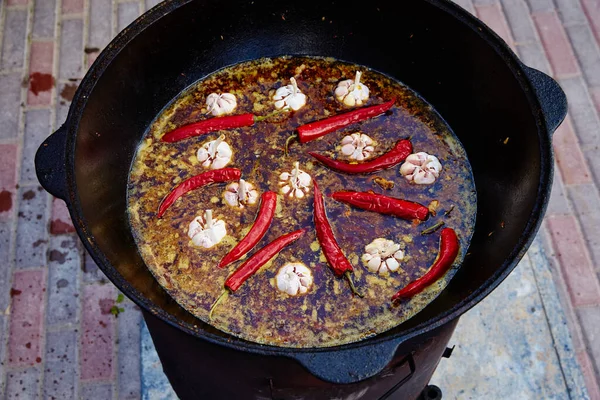 Ulusal Özbek yemeği pilavı, pilav, pilav, pilav, büyük tavada etli pilav. Kazanda ateşte pişirme işlemi. Hazırlık safhası. Pirinç dök, su ekle, kırmızı biber ve tüm sarımsağı ekle. — Stok fotoğraf