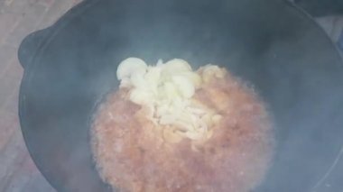 Ulusal Özbek yemeği pilavı, pilav, pilav, pilav, büyük tavada etli pilav. Pişirme işlemi, ateş açın. Kazanda ateşte yemek pişirmek. Hazırlık aşamaları. Karamel ve pilau renginde kızartılmış soğanlar.