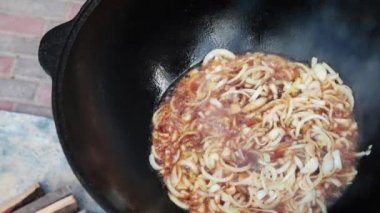Ulusal Özbek yemeği pilavı, pilav, pilav, pilav, büyük tavada etli pilav. Pişirme işlemi, ateş açın. Kazanda ateşte yemek pişirmek. Hazırlık aşamaları. Karamel ve pilau renginde kızartılmış soğanlar.