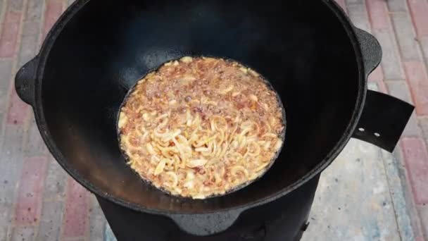 National Uzbek dish pilaf, pilaw, plov, rice with meat in big pan. Cooking process, open fire. Cooking in a cauldron on fire. Preparation stages. Onions roasting to color of caramel, pilau — Stock Video