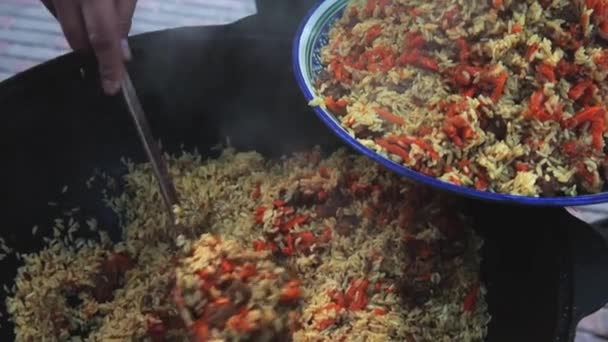 Nationale Oezbeekse schotel pilaf, pilaw, plov, rijst met vlees in grote pan. Naar de grote plaat, ketel in brand, wortel. — Stockvideo
