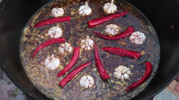 Národní uzbecký pilaf, pilaf, plov, rýže s masem ve velké pánvi. Proces vaření v kotli v ohni. Přidat červený pepř a česnek — Stock video