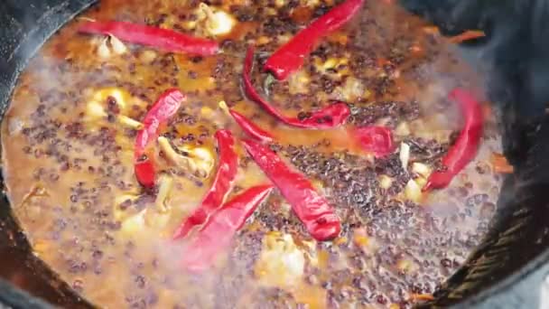 Plato nacional uzbeko pilaf, pilaw, plov, arroz con carne en sartén grande. Sacar el ajo, proceso de cocción en un caldero a fuego, pimiento rojo y todo el ajo — Vídeo de stock