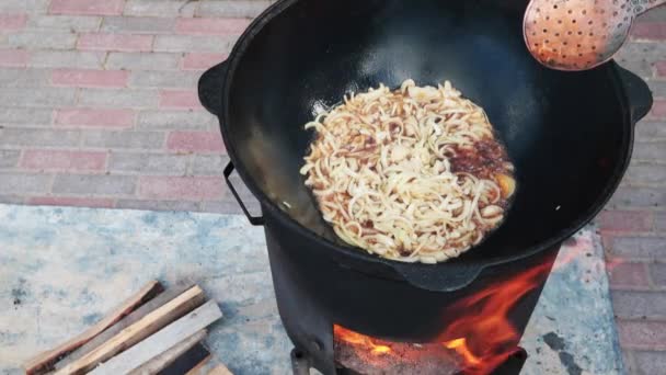 Plato nacional uzbeko pilaf, pilaw, plov, arroz con carne en sartén grande. Proceso de cocción, fuego abierto. Cocinar en un caldero en llamas. Etapas de preparación. La cebolla asando hasta el color del caramelo, pilau — Vídeo de stock