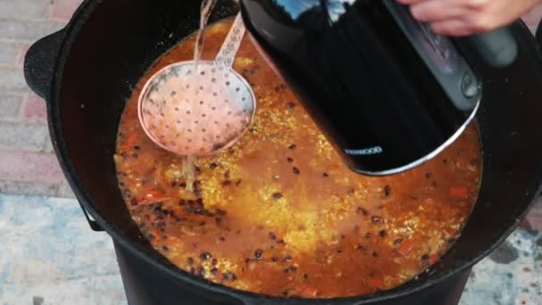 乌孜别克族菜饭、毛皮、麦片、大锅饭、肉饭.把煮好的煮好的过程放在一个大锅里，把火，红辣椒和整个大蒜放进锅里 — 图库视频影像