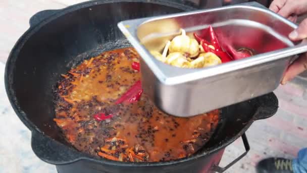 Plat ouzbek national pilaf, pilaw, plov, riz avec viande dans une grande casserole. Sortir le poivron rouge et l'ail, faire cuire dans un chaudron sur le feu, le poivron rouge et l'ail entier 