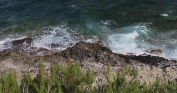 海浪在岩石的岩脉、法国南部的费拉角、蓝色海岸的堤岸、高山和蓝天的衬托下破浪而出, — 图库视频影像