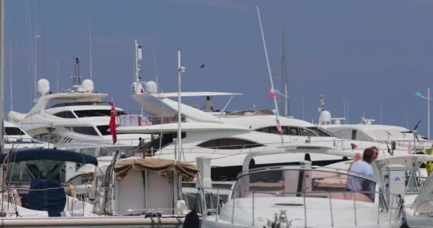 Francia, Port Saint-Jean-Cap-Ferrat, 29 maggio 2017: La coppia di anziani parcheggia lo yacht, un molo, megayachts sullo sfondo, tempo soleggiato — Video Stock