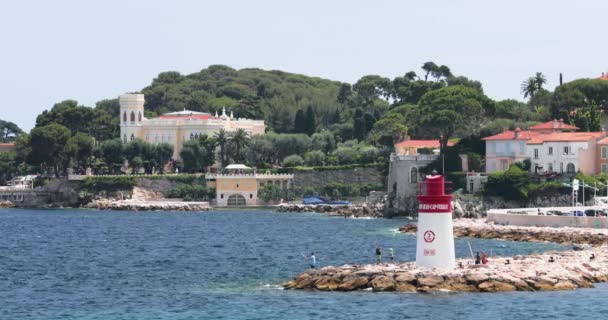 Francia, Saint-Jean-Cap-Ferrat, 29 de mayo de 2017: El faro en el puerto, los megayates están en el horizonte acuático, el agua azul, muchos barcos de pesca y yates, un muelle, la playa de Paloma — Vídeos de Stock