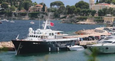 Fransa, Saint-Jean-Cap-Ferrat, 29 Mayıs 2017: Limandaki deniz feneri, mega yatlar su ufku, gök mavisi su, bir sürü balıkçı teknesi ve yat, bir rıhtım, Paloma plajı