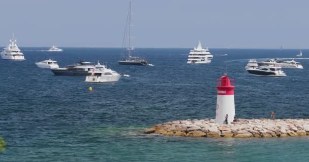 Франция, Сен-Жан-Кап-Ферра, 29 мая 2017: Маяк в порту, мега яхты на водном горизонте, лазурная вода, много рыбацких лодок и яхт, пирс, пляж Палома — стоковое видео