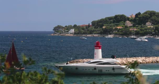 Francja, Saint-Jean-Cap-Ferrat, 29 maja 2017: Latarnia morska w porcie, mega jachty są na horyzoncie wodnym, lazurowa woda, dużo łodzi rybackich i jachtów, pomost, plaża Paloma — Wideo stockowe