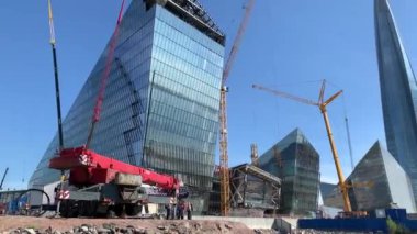 Rusya, St.Petersburg, 26 Mayıs 2020: Herkül Limanı, büyük endüstriyel vinç yelkenliyi kaldırır ve yüzdürür, yelkencilik mevsiminin başlangıcı, arka planda bir gökdelen, yelkenli yersizdir